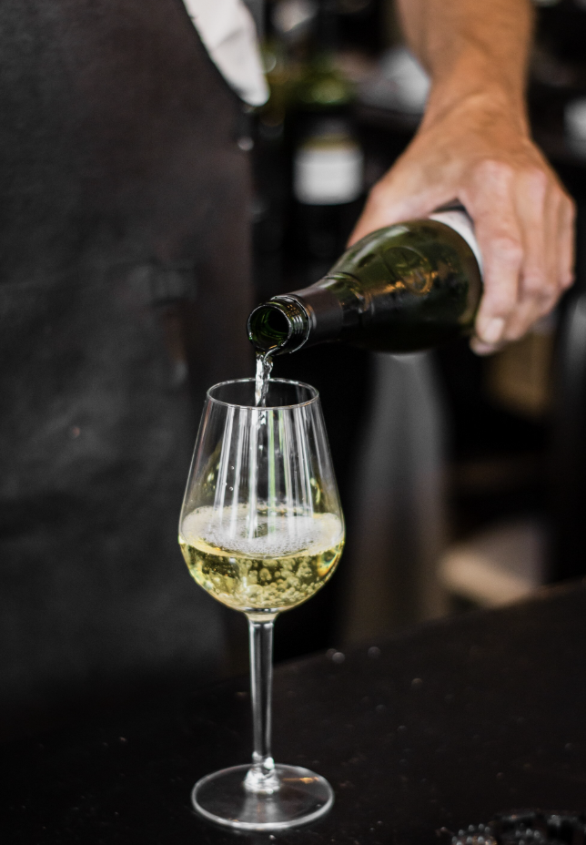 A bottle of wine being poured into a glass of wine