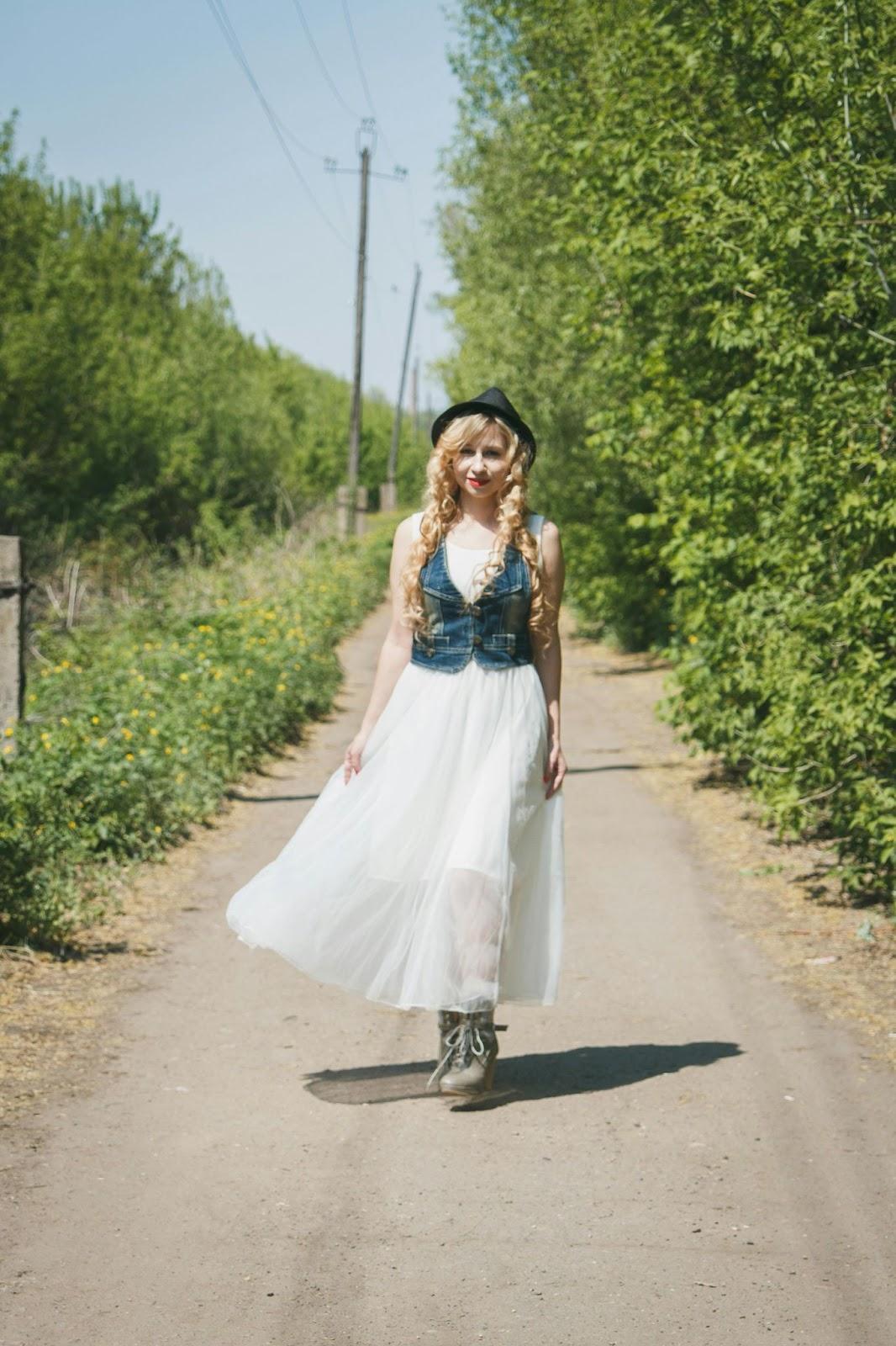 A woman wearing a flowy skirt and denim vest