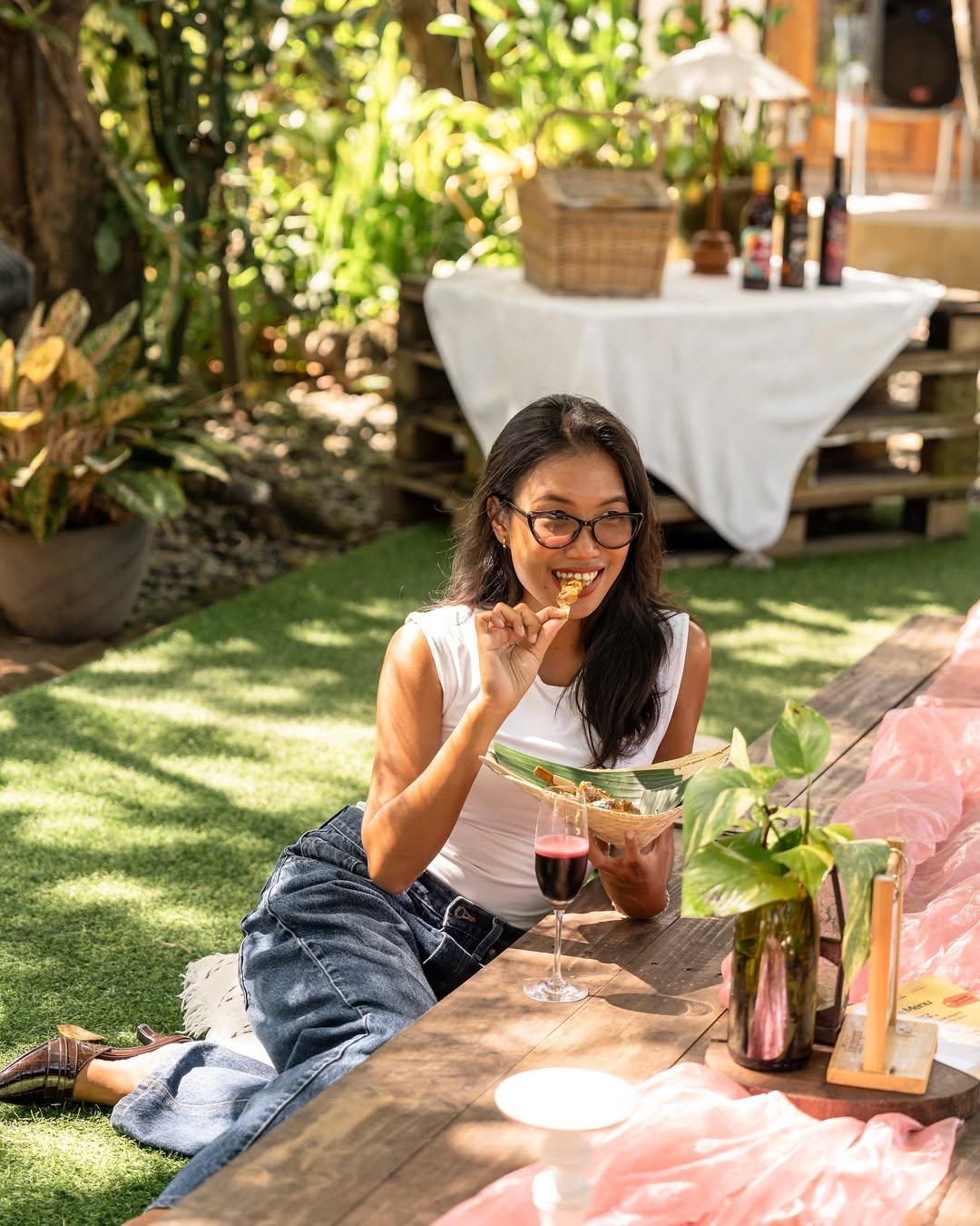 A woman eating some snacks in the garden at Sabaday Winery Bali