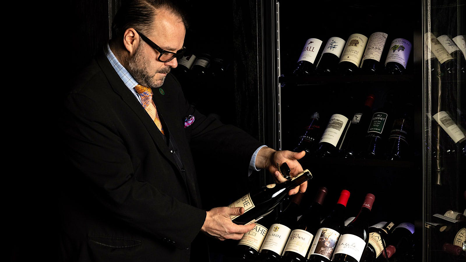 A man checking a bottle of wine from a selection of wines