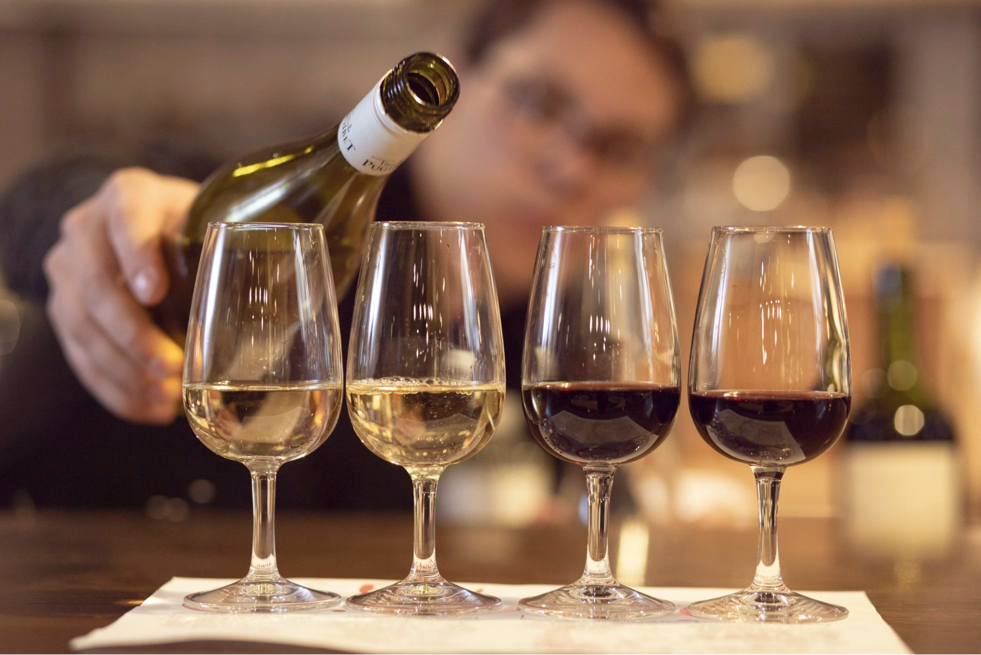 A flight of four wine glasses being poured