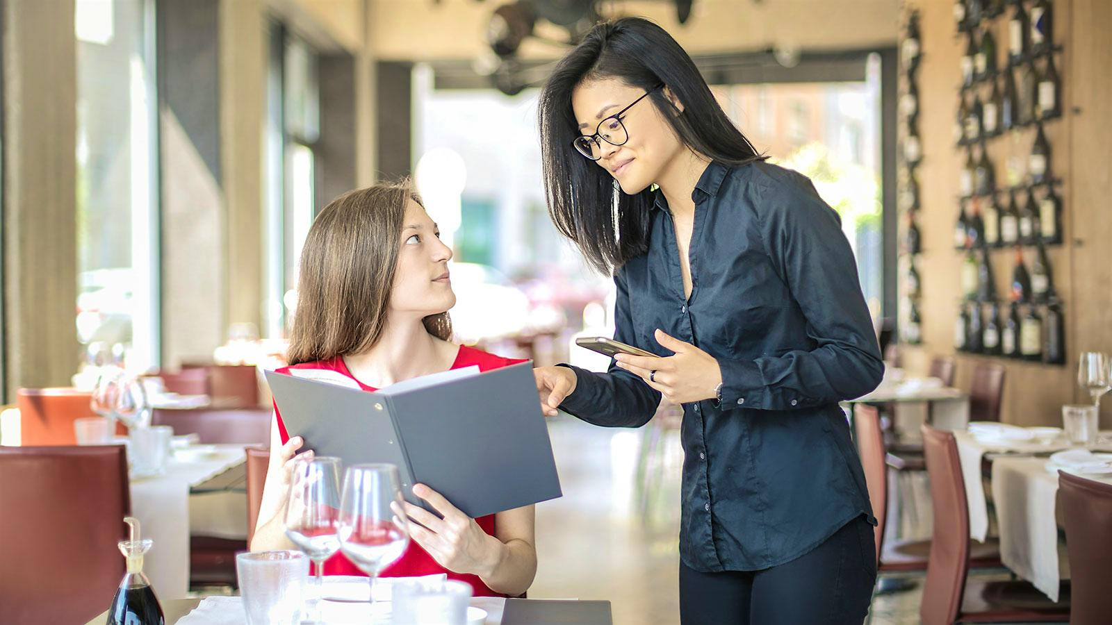 A staff at a wine bar taking the order of a customer
